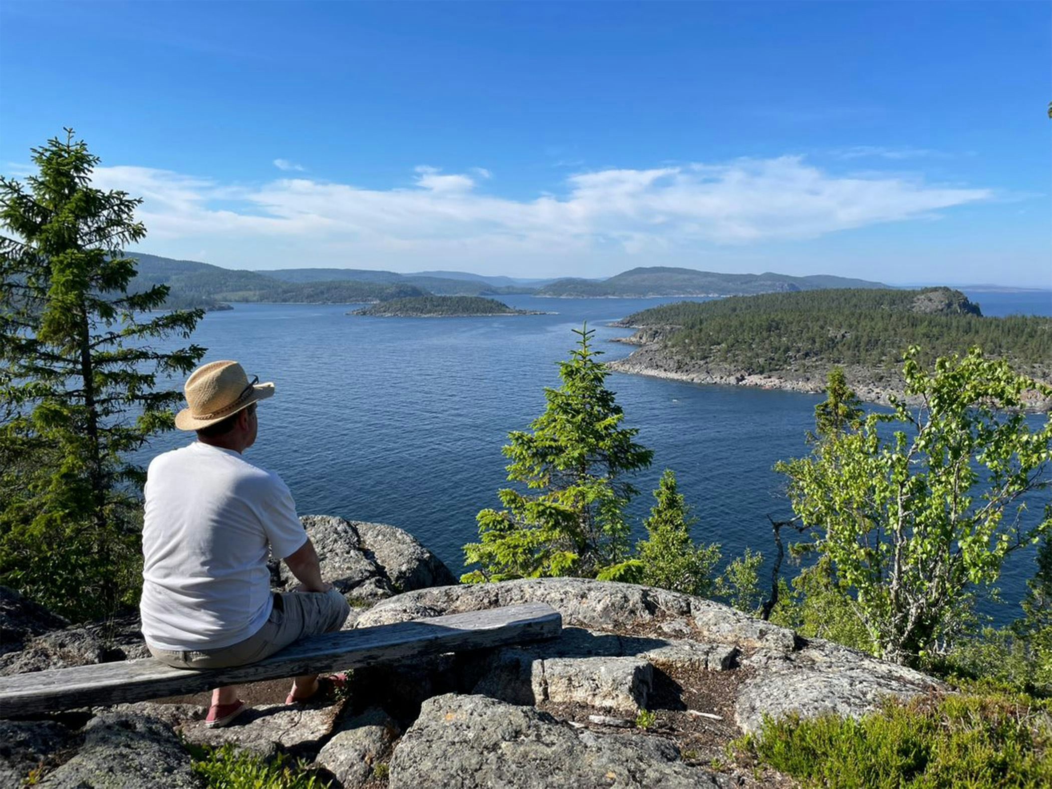 Person sitter på en klippa och blickar ut över hav, öar och skärgårdslandskap från en utsiktsplats.