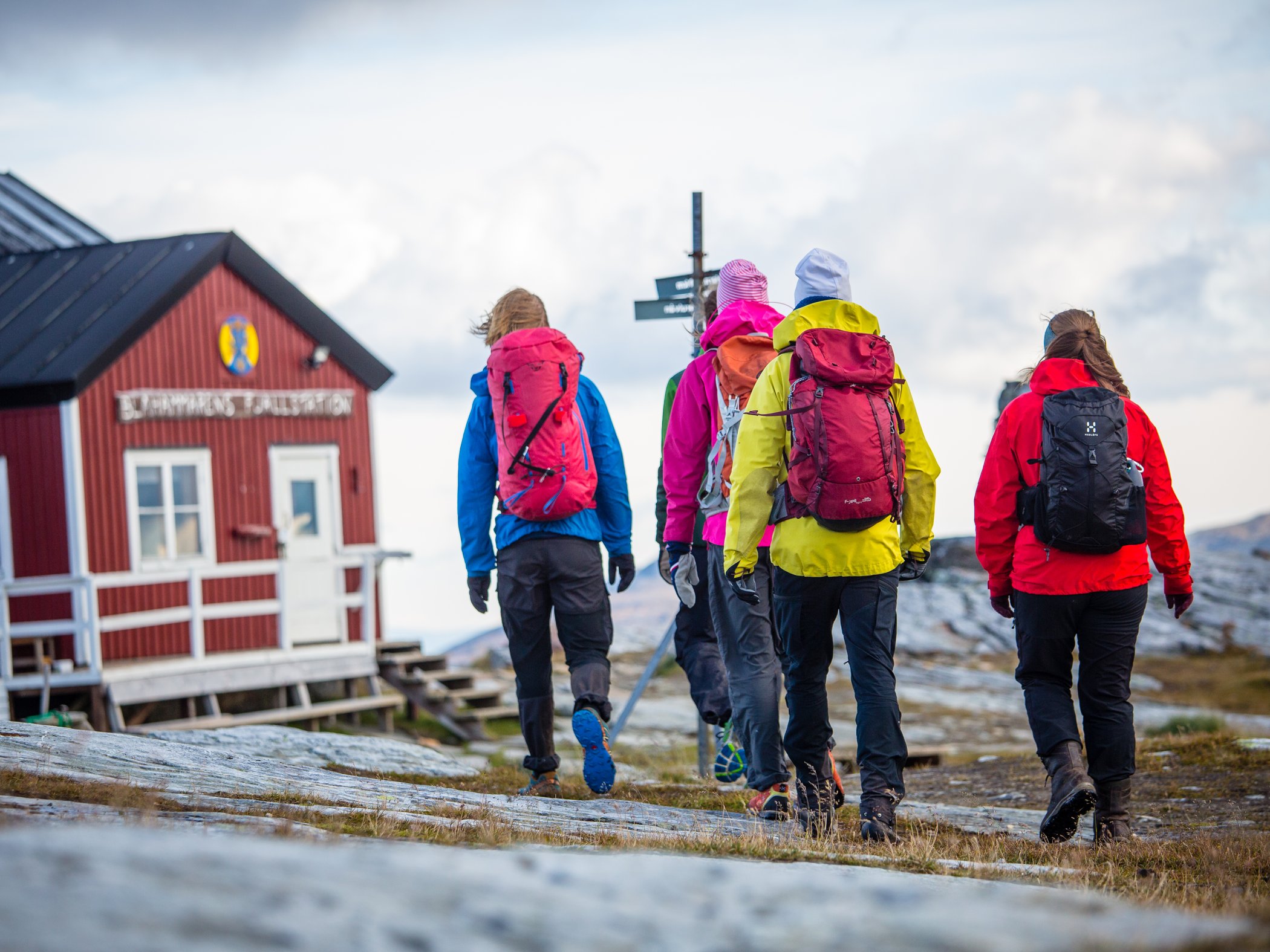Vandrare med ryggsäckar går förbi STF Sylarna fjällstation.