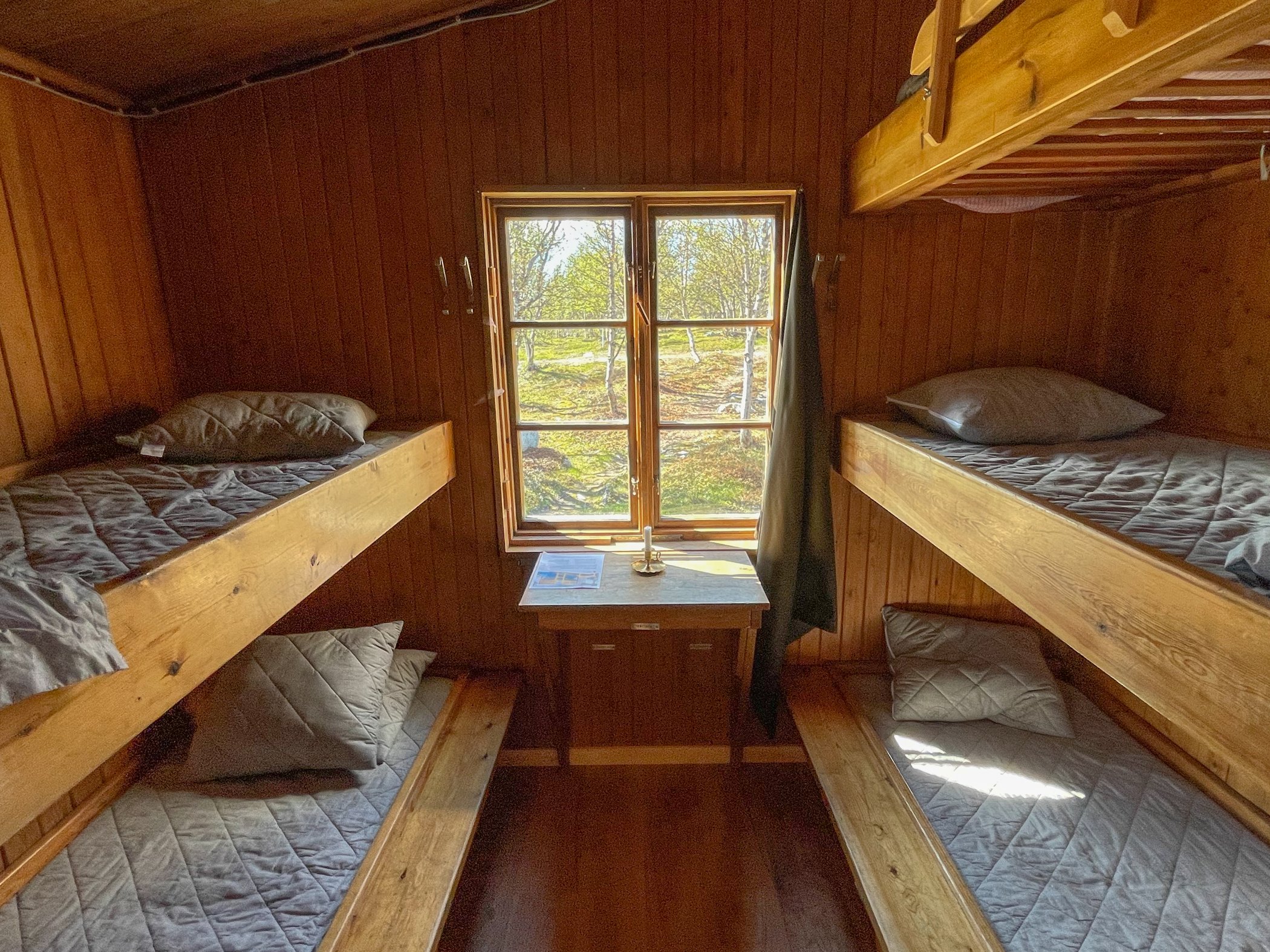 Fyrbäddsrum med våningssängar och träinredning i fjällstuga.