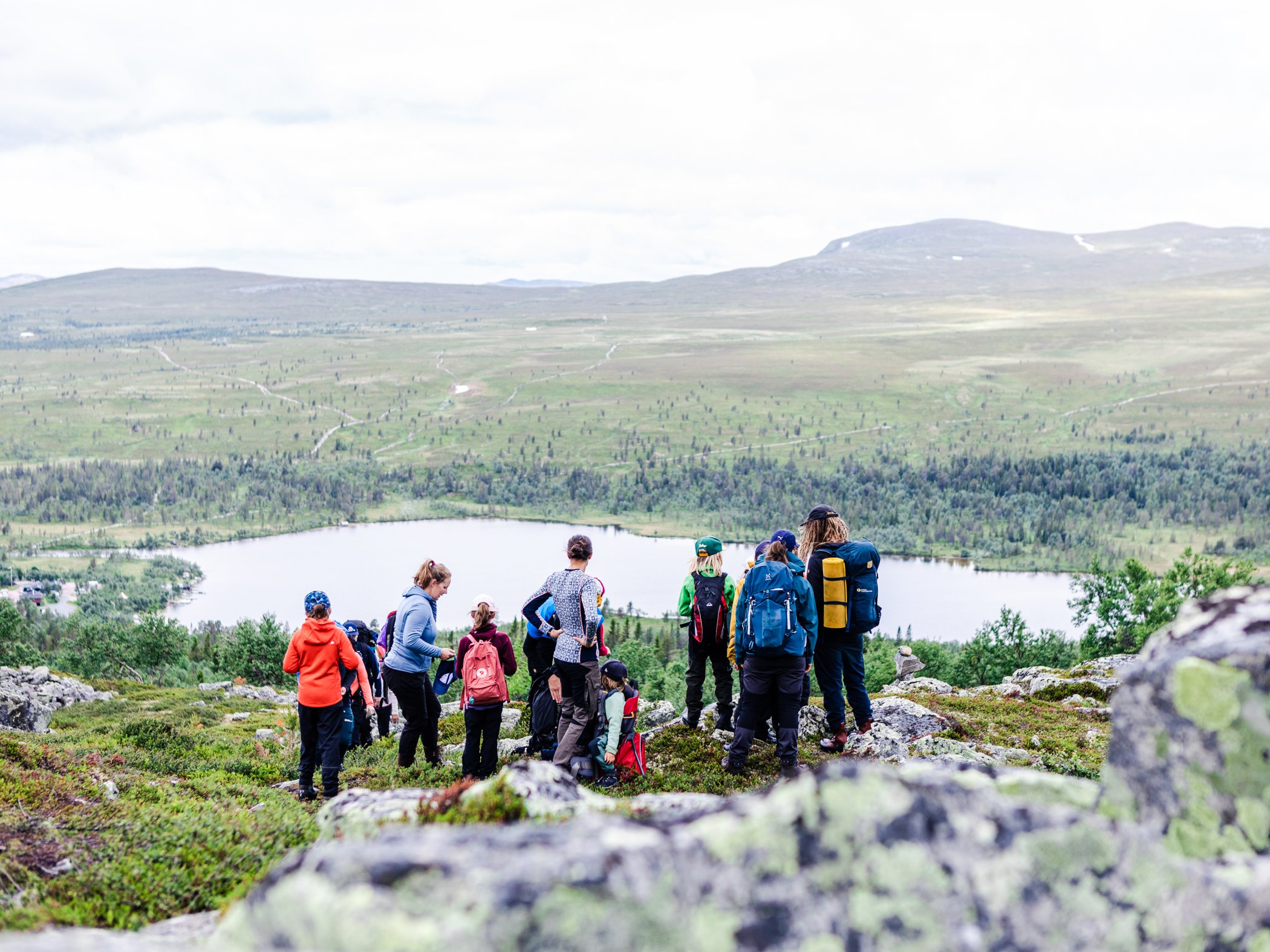 Grupp vandrare blickar ut över fjällandskap och sjö nära Grövelsjön.