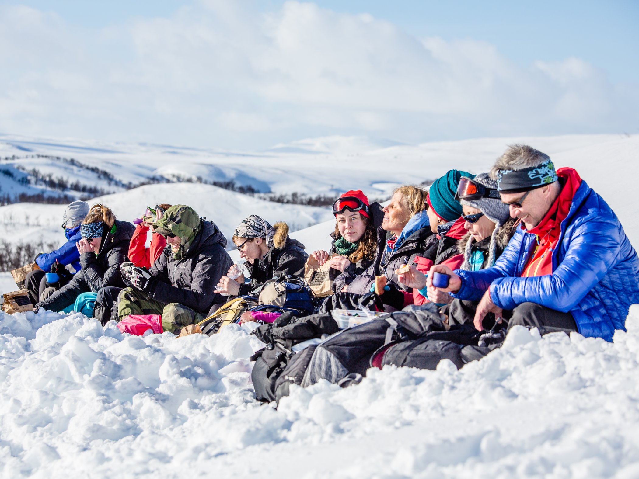 En grupp människor som sitter i snö och njuter i solen.