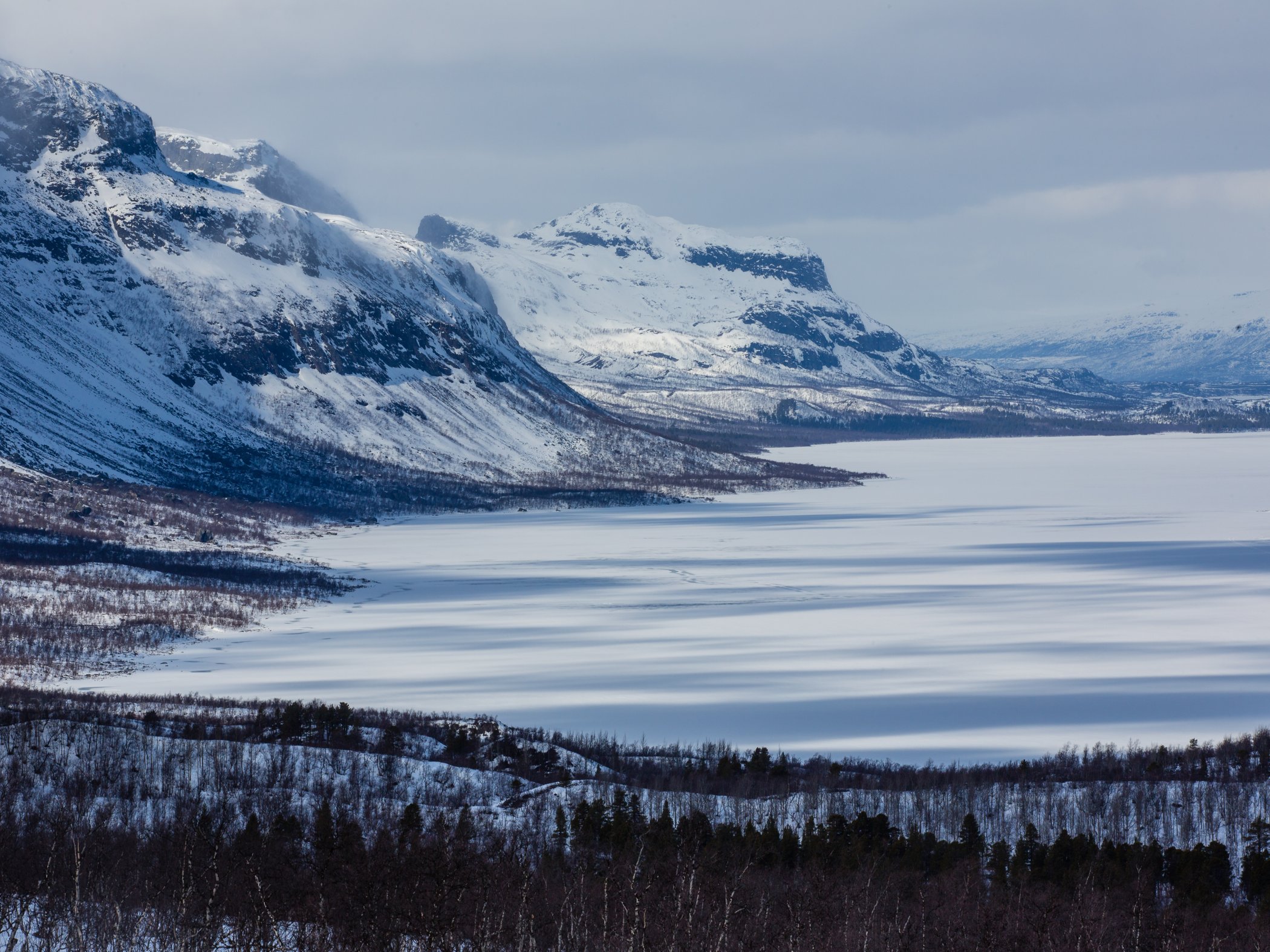 En storslagen utsikt över en sjö och fjäll med snö.