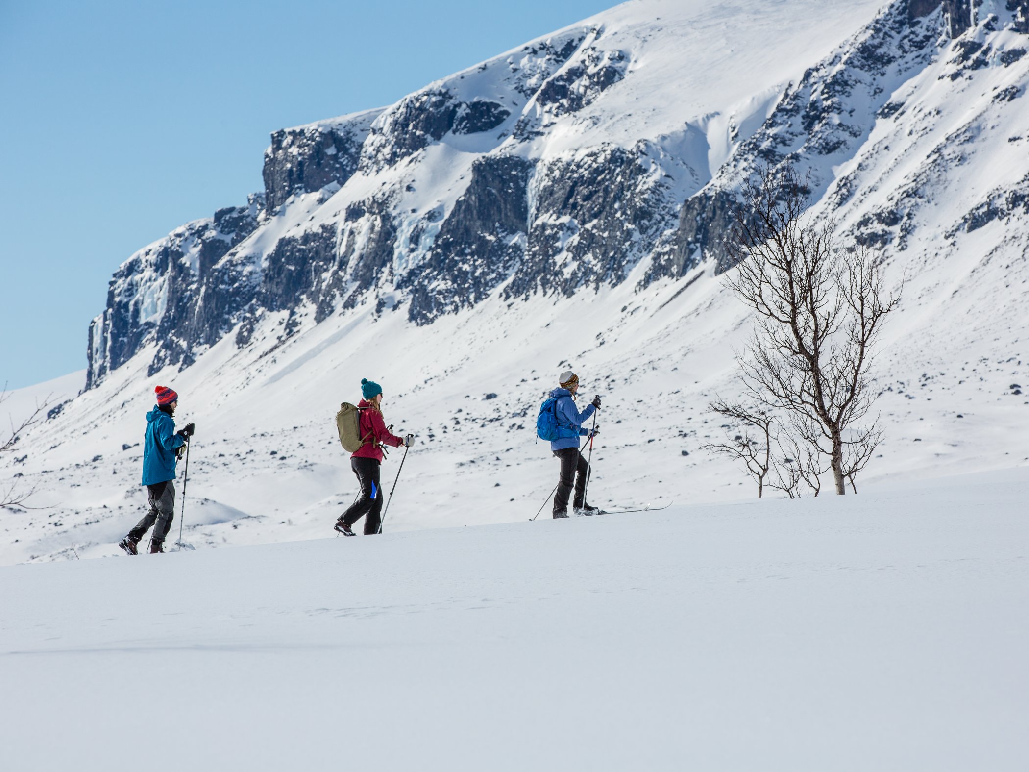 tre människor som går i snö med turskidor.