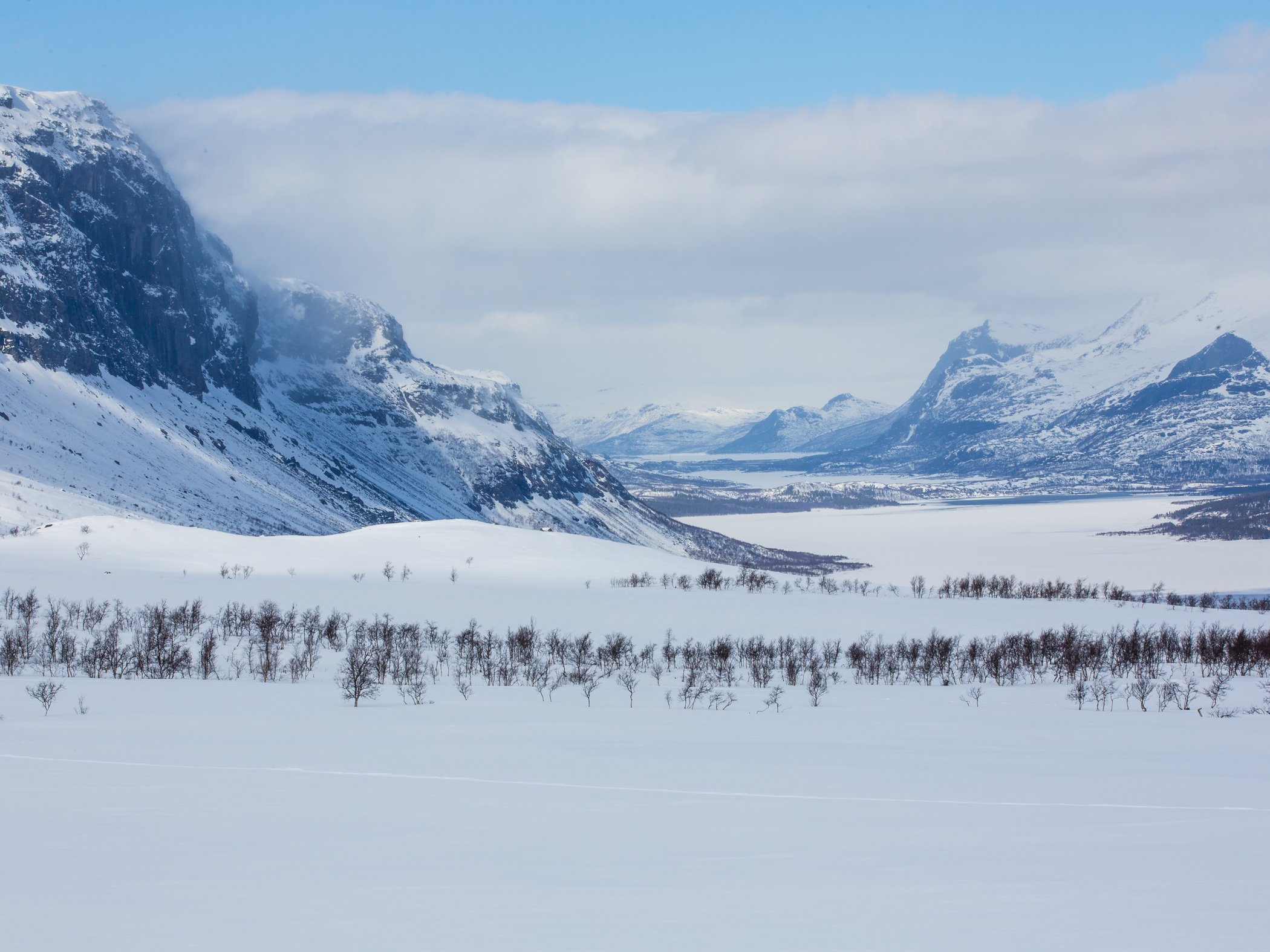 utsikt över snöklädda fjäll och en sjö.