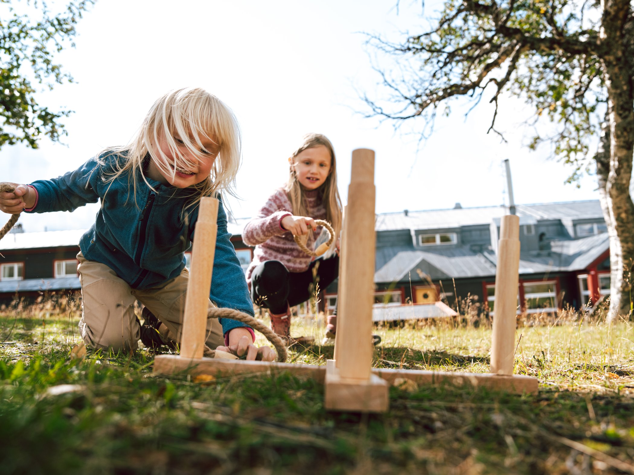 Barn spelar kubb utomhus vid fjällstation.
