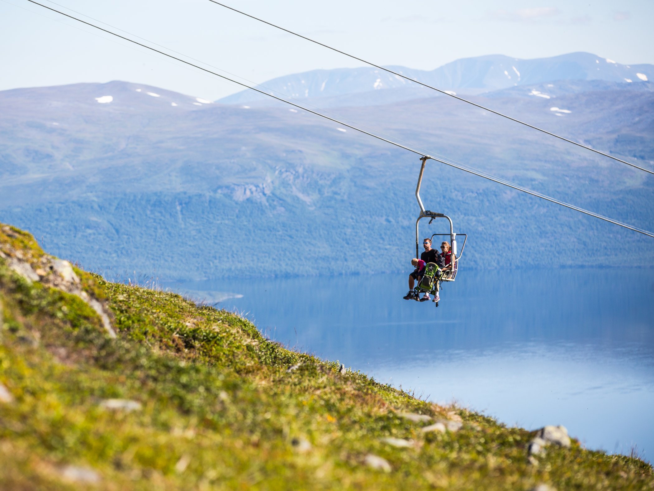 Personer åker stollift med utsikt över Torneträsk i Abisko.