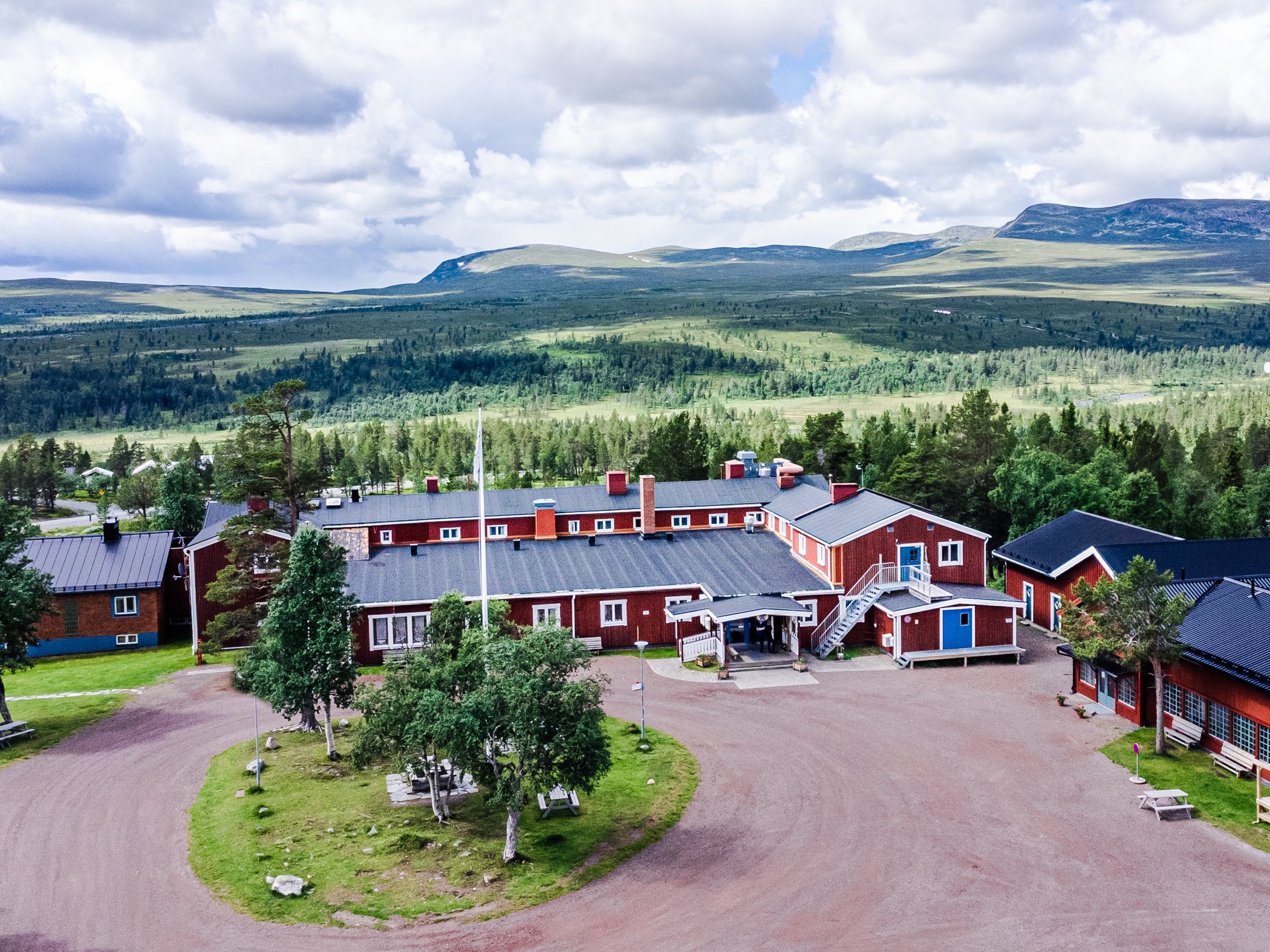 Flygfoto över STF Grövelsjön Fjällstation med fjällen i bakgrunden.