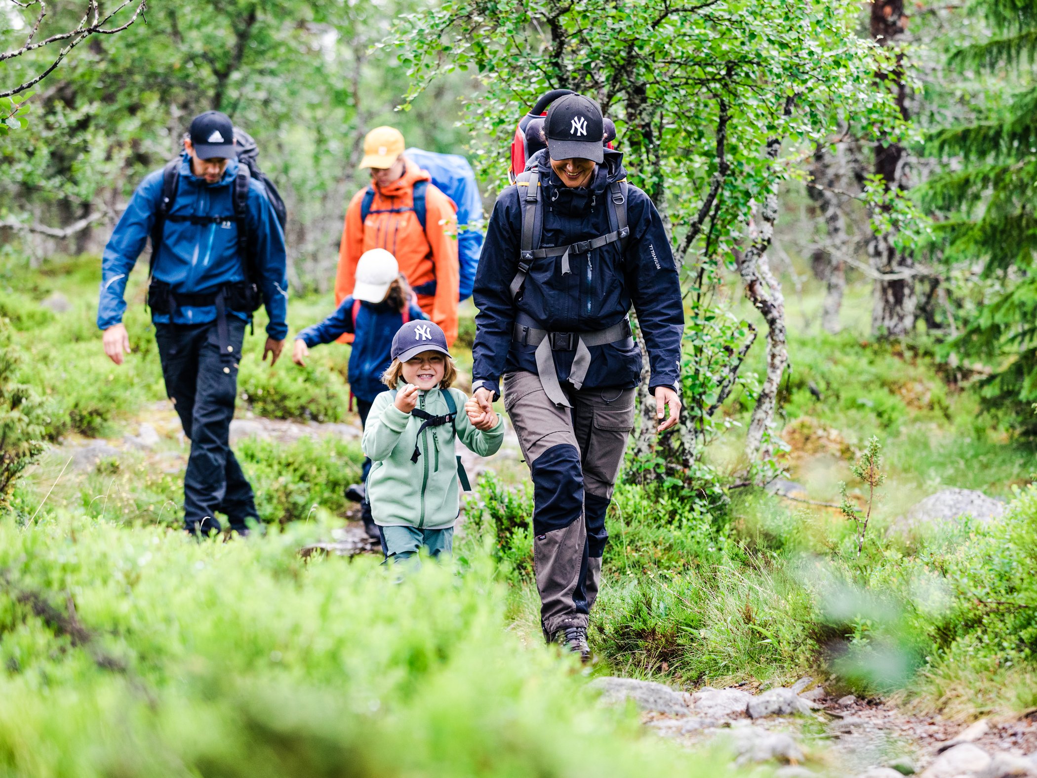 Familj med ryggsäckar vandrar genom fjällskog nära Grövelsjön.