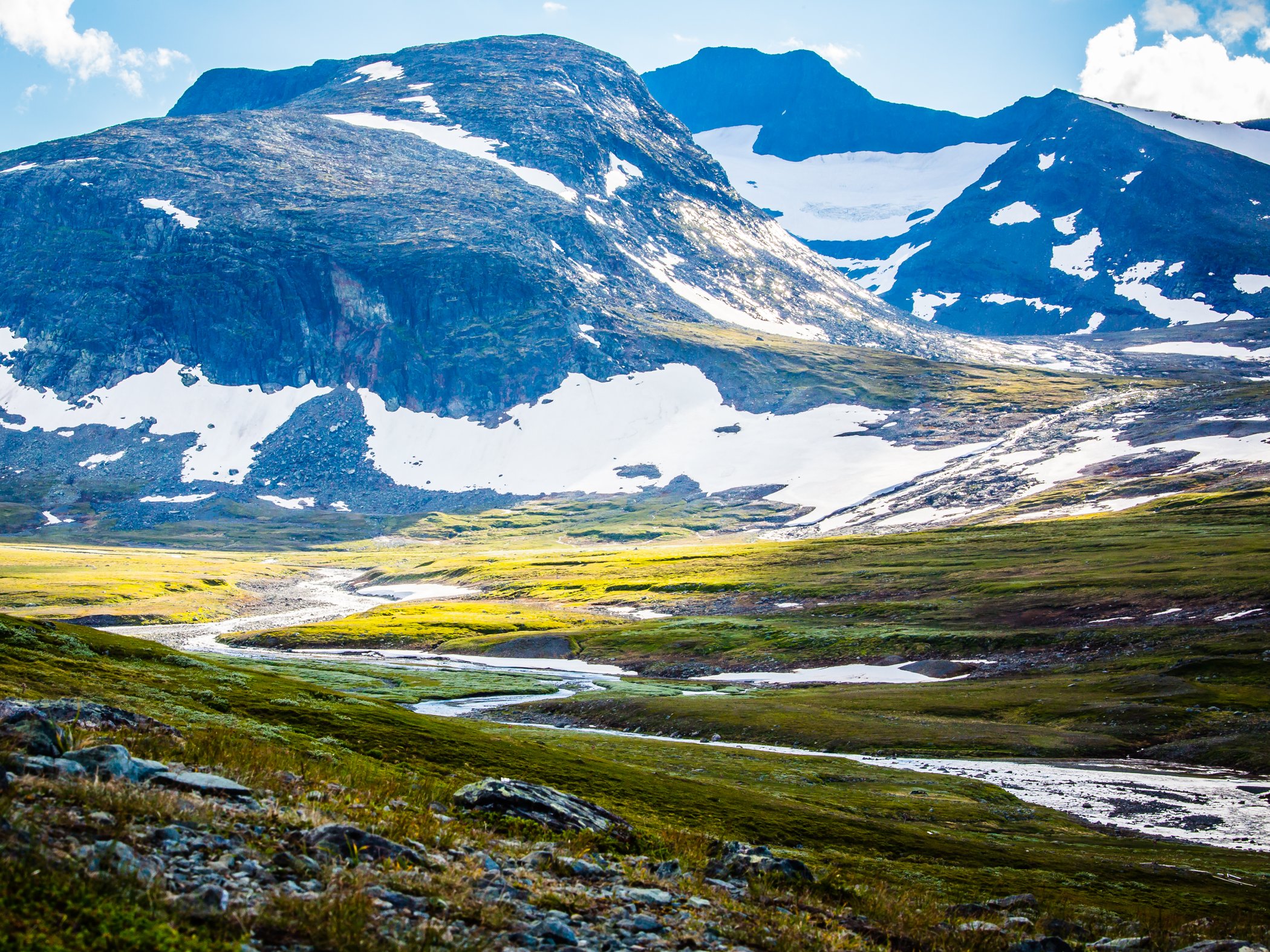 Fjällandskap med Helagsmassivet, snölegor och slingrande vattendrag.