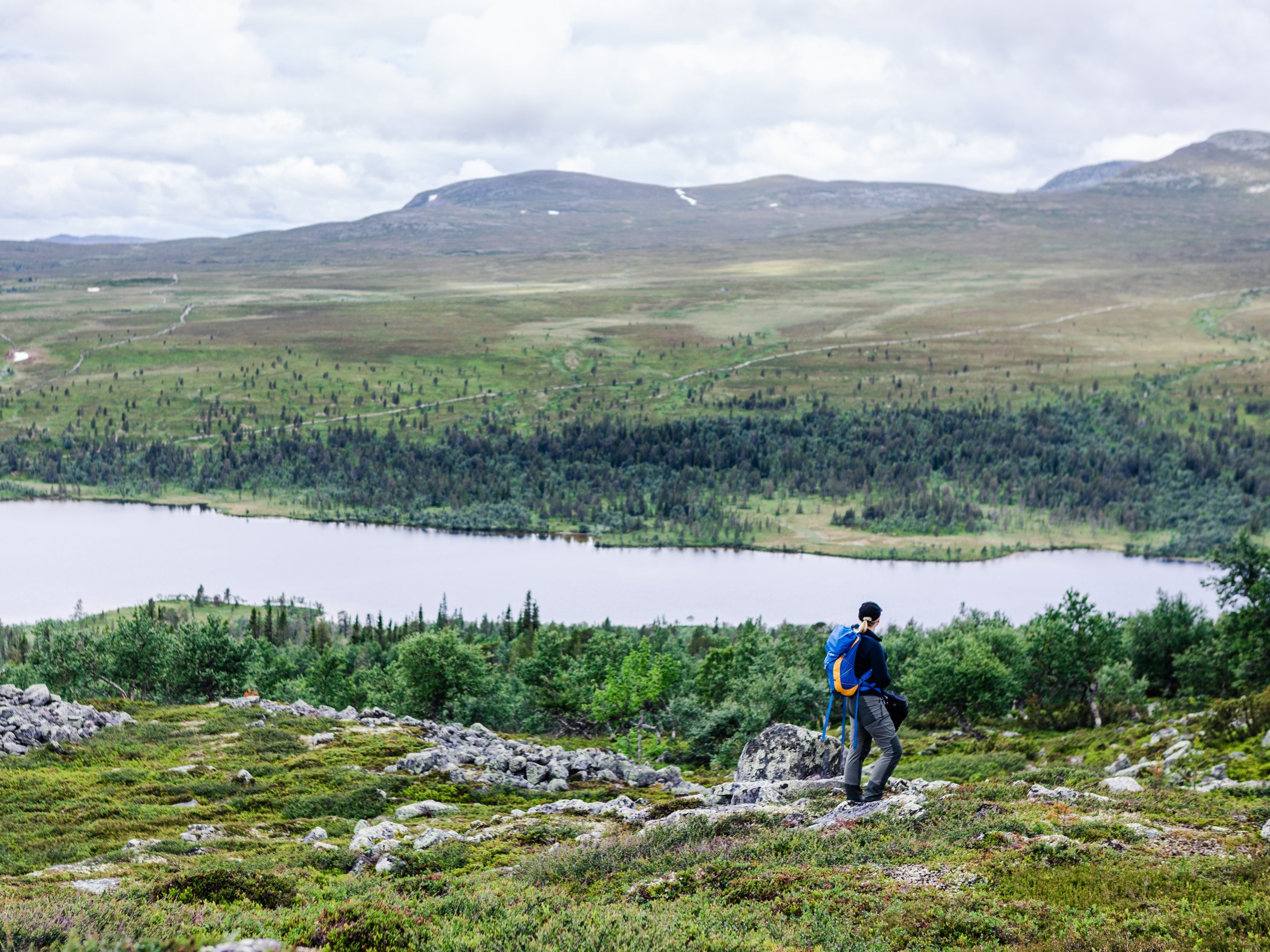 Vandrare med ryggsäck blickar ut över sjö och fjällandskap nära Grövelsjön.
