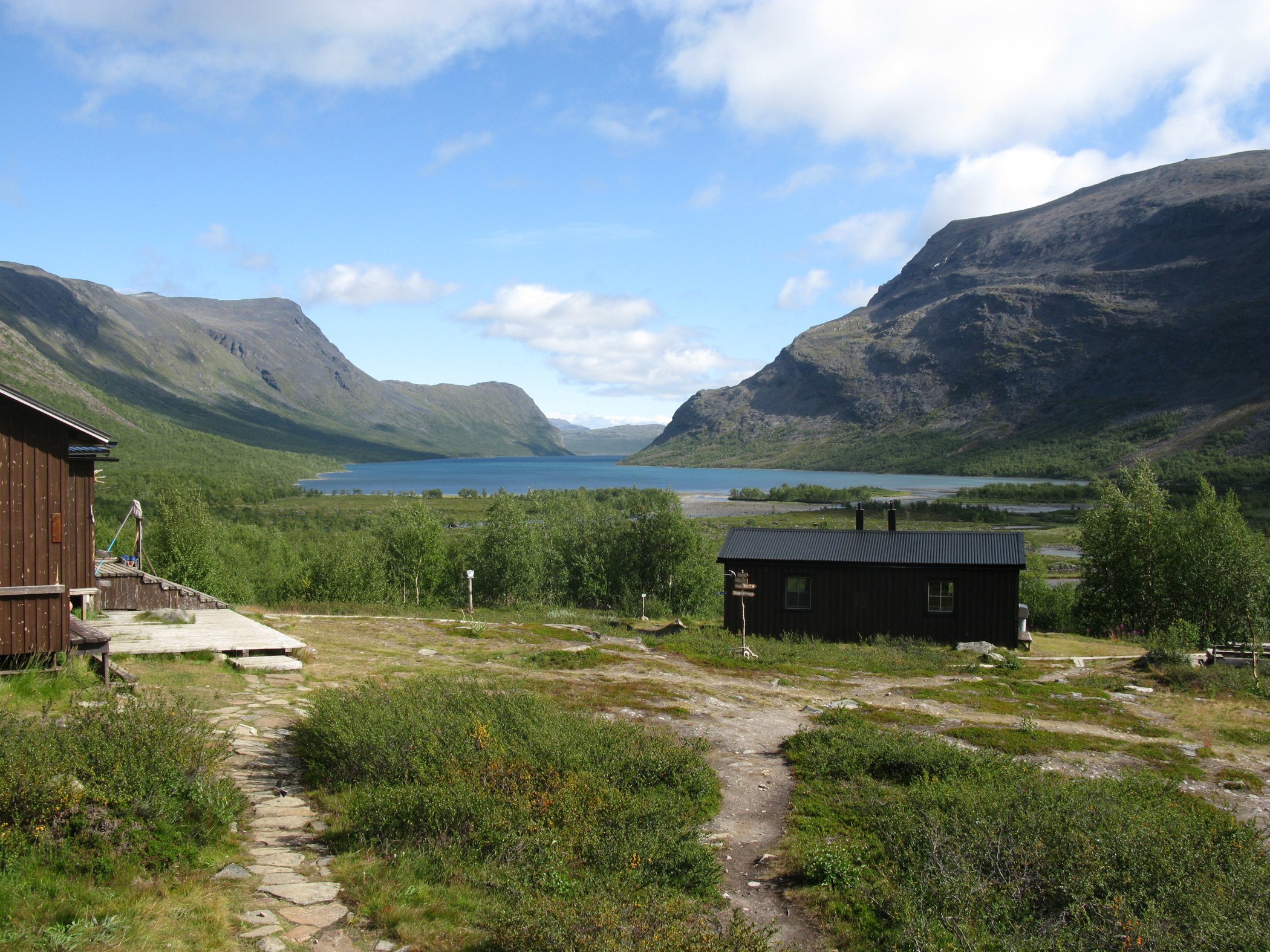 Utsikt över Kaitumjaure med fjäll, sjö och STF-stugor.