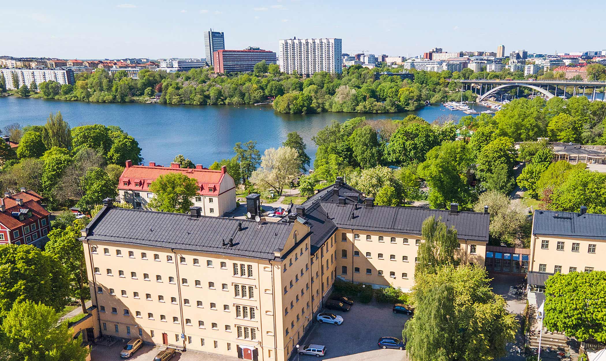 Flygfoto över Långholmen med byggnader, grönområden och vatten i Stockholm.