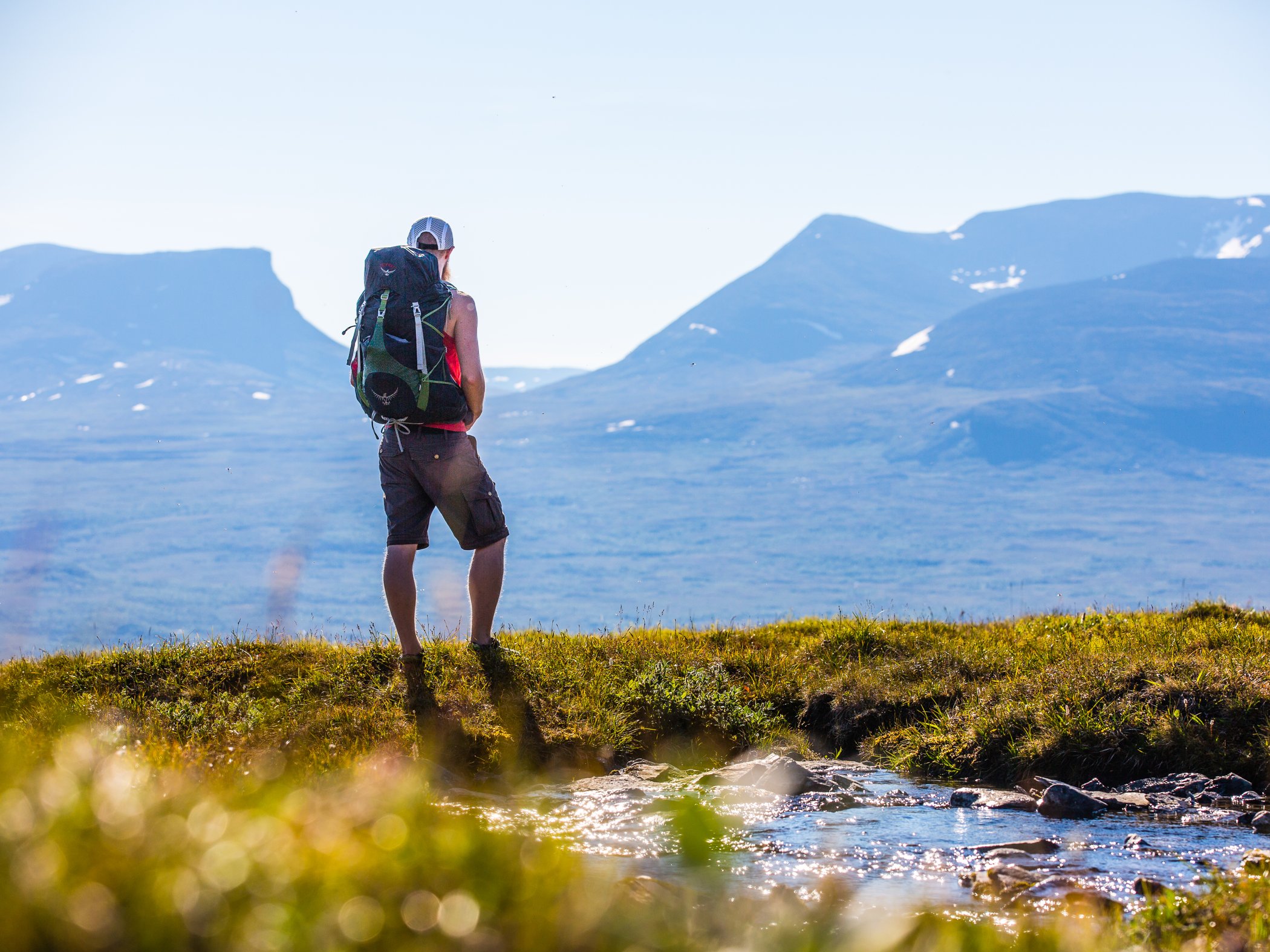 Vandrare med ryggsäck blickar ut över fjällandskap.