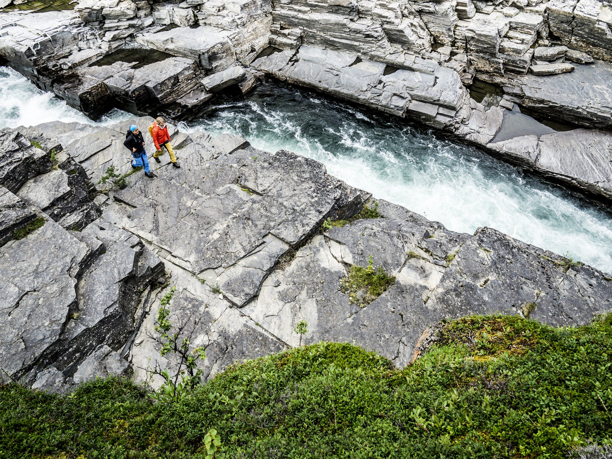 Vandrare vid klippformationer och forsande vatten i Abisko.