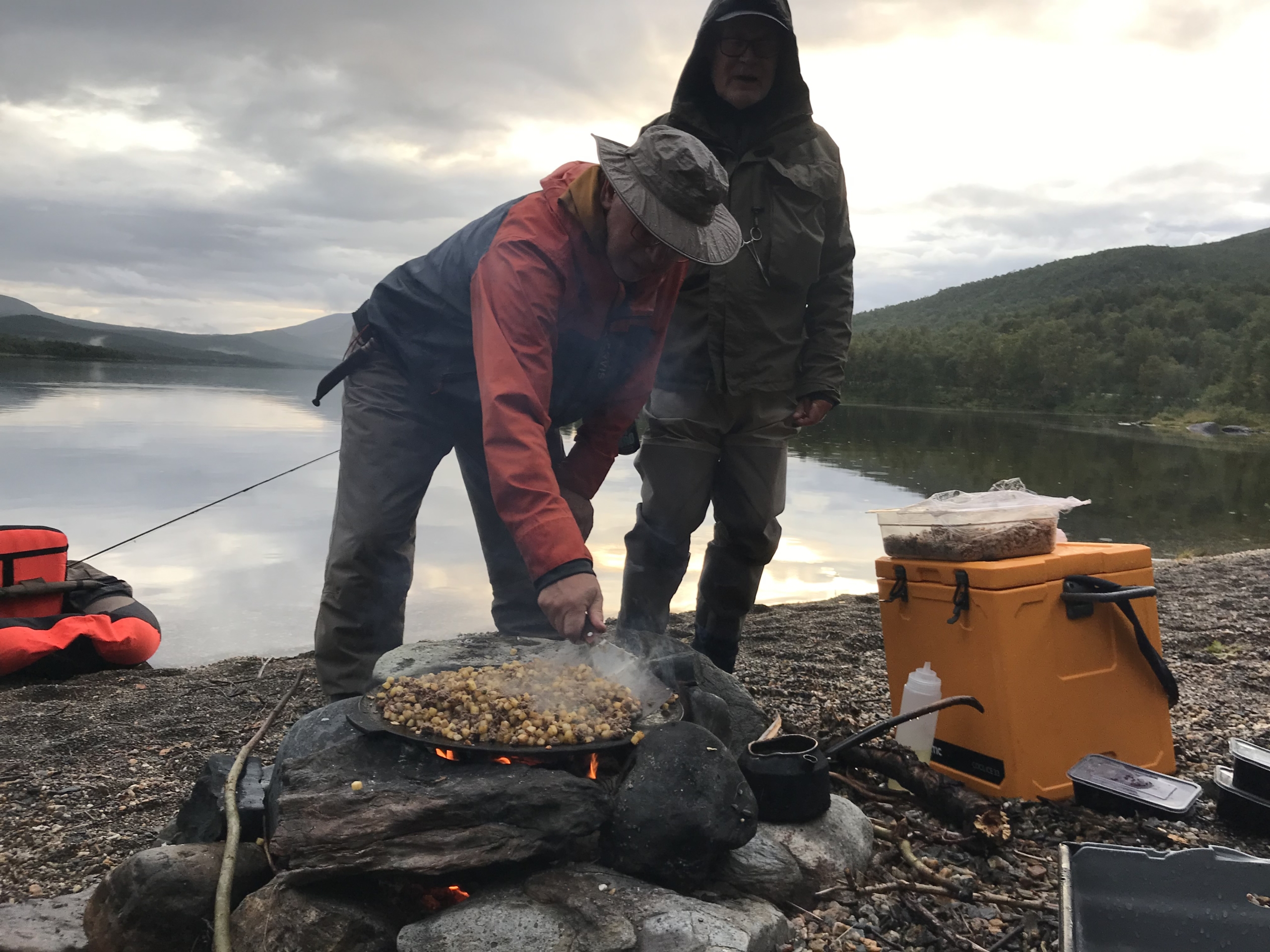 2 fiskare som rensar en fisk vid en sjö.