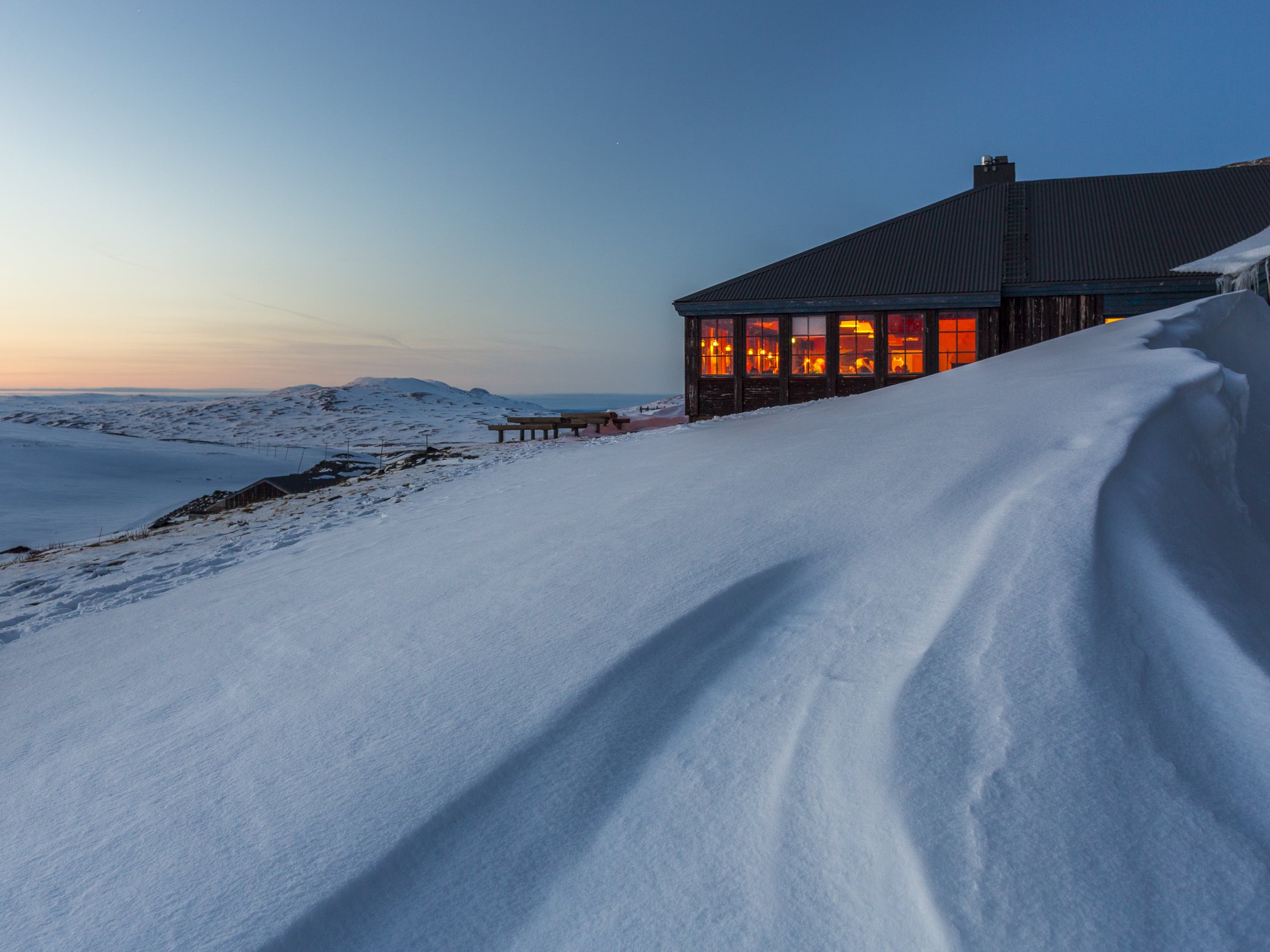 En kvällsbild med en fjällstation i snö.