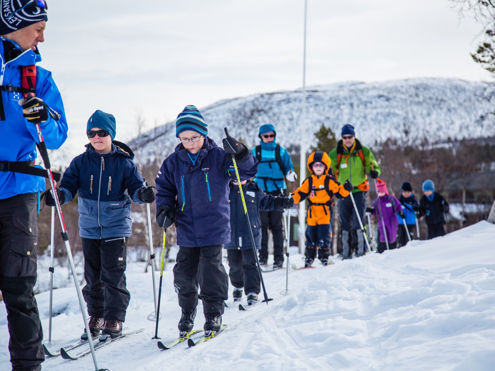 Barn på längdskidor i vinterlandskapet under en familjeaktivitet i fjällen.