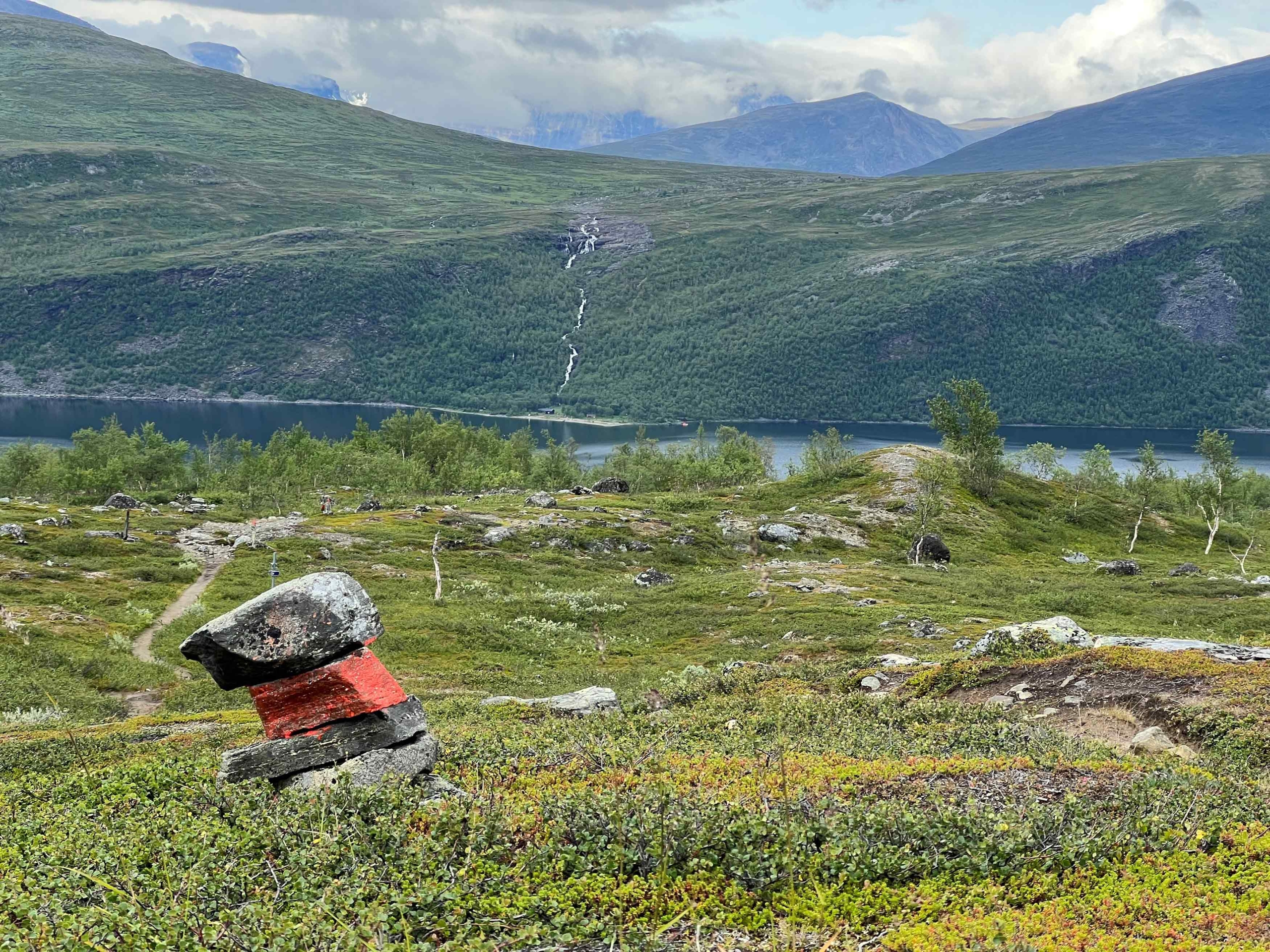 Ledmarkering i fjällandskap med sjö och fjäll i bakgrunden.