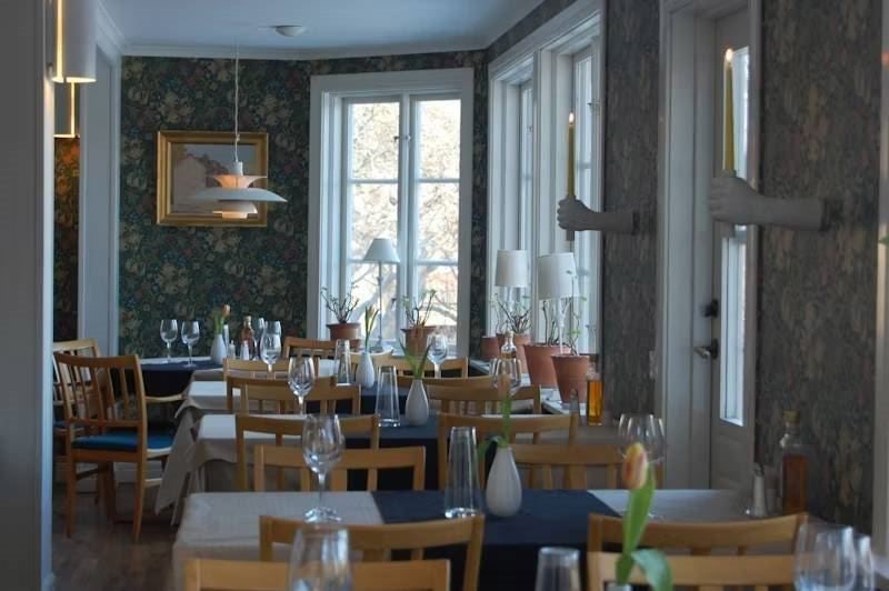 Ljus och inbjudande matsal med dukade bord och fönster som släpper in dagsljus.