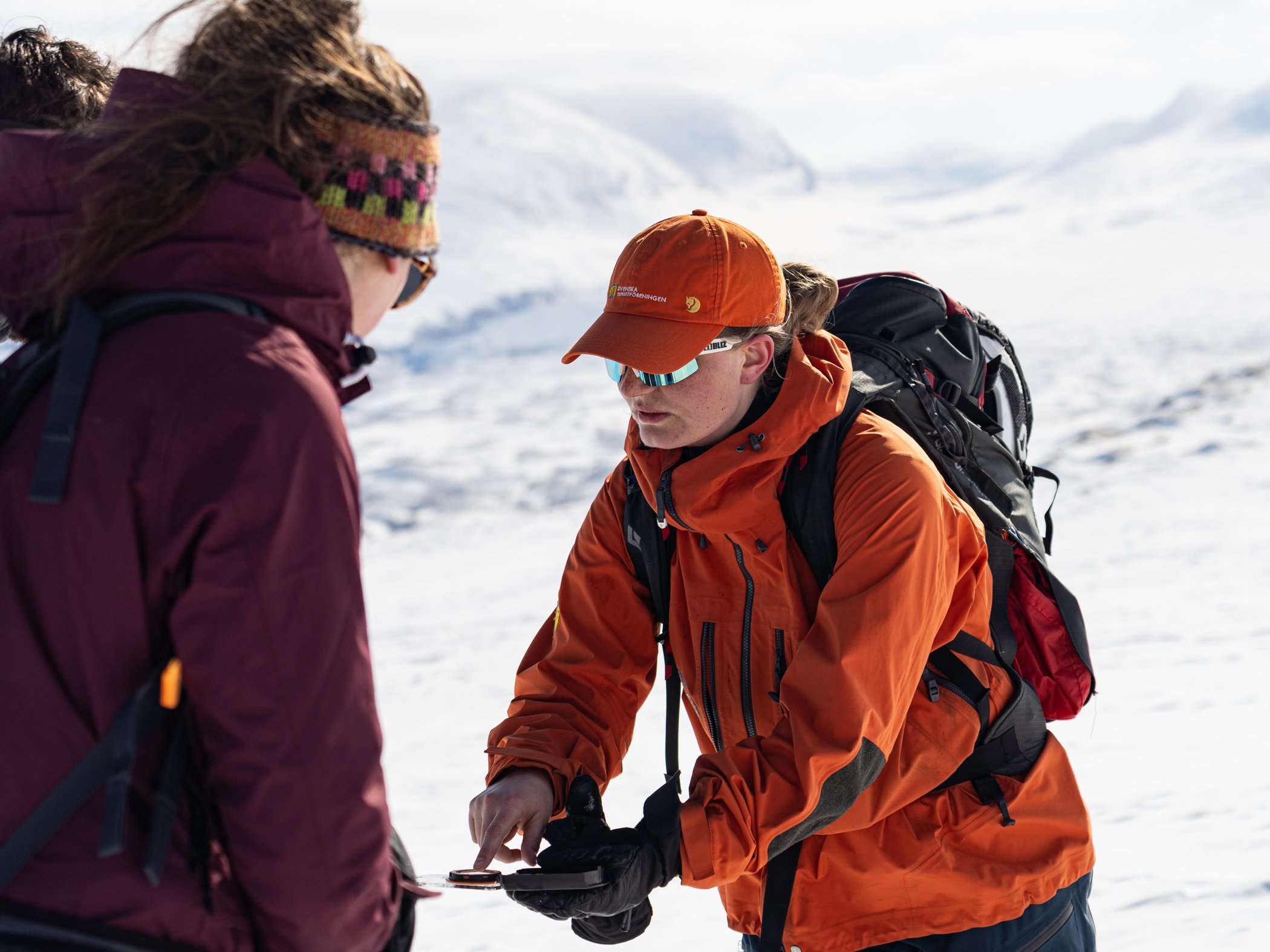 Privatguide visar navigering med karta och kompass för deltagare i vinterfjäll.