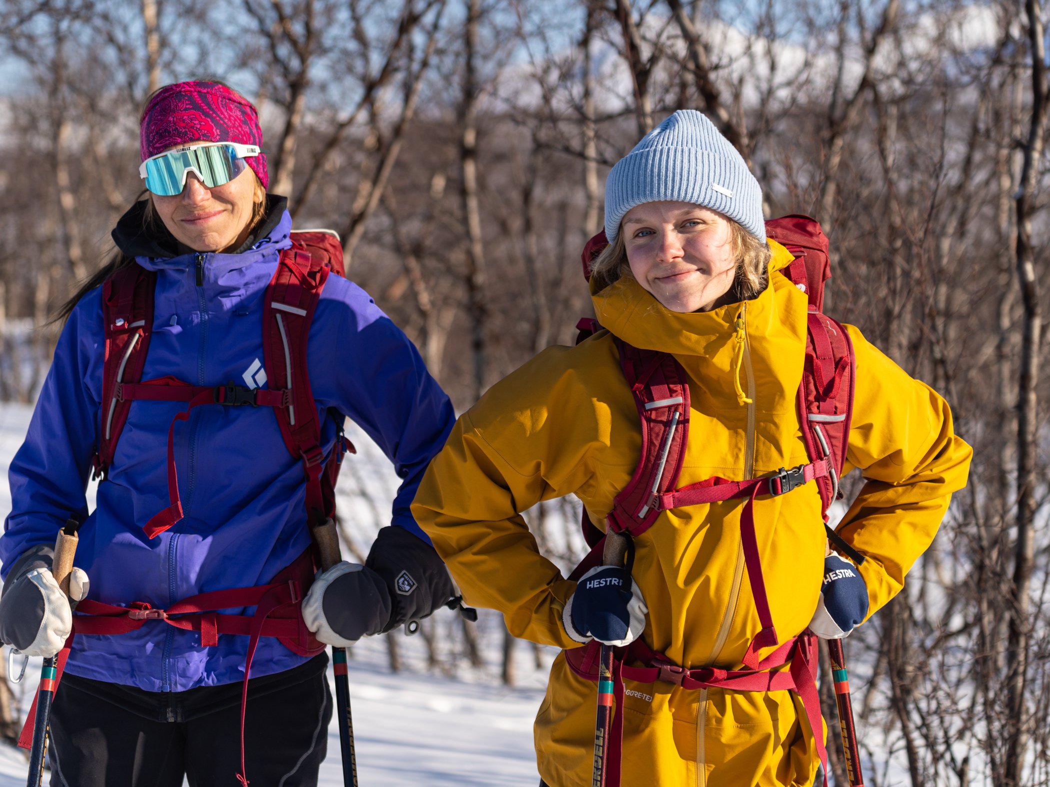 Två deltagare på turskidtur i Abisko står med skidstavar i vinterlandskapet.
