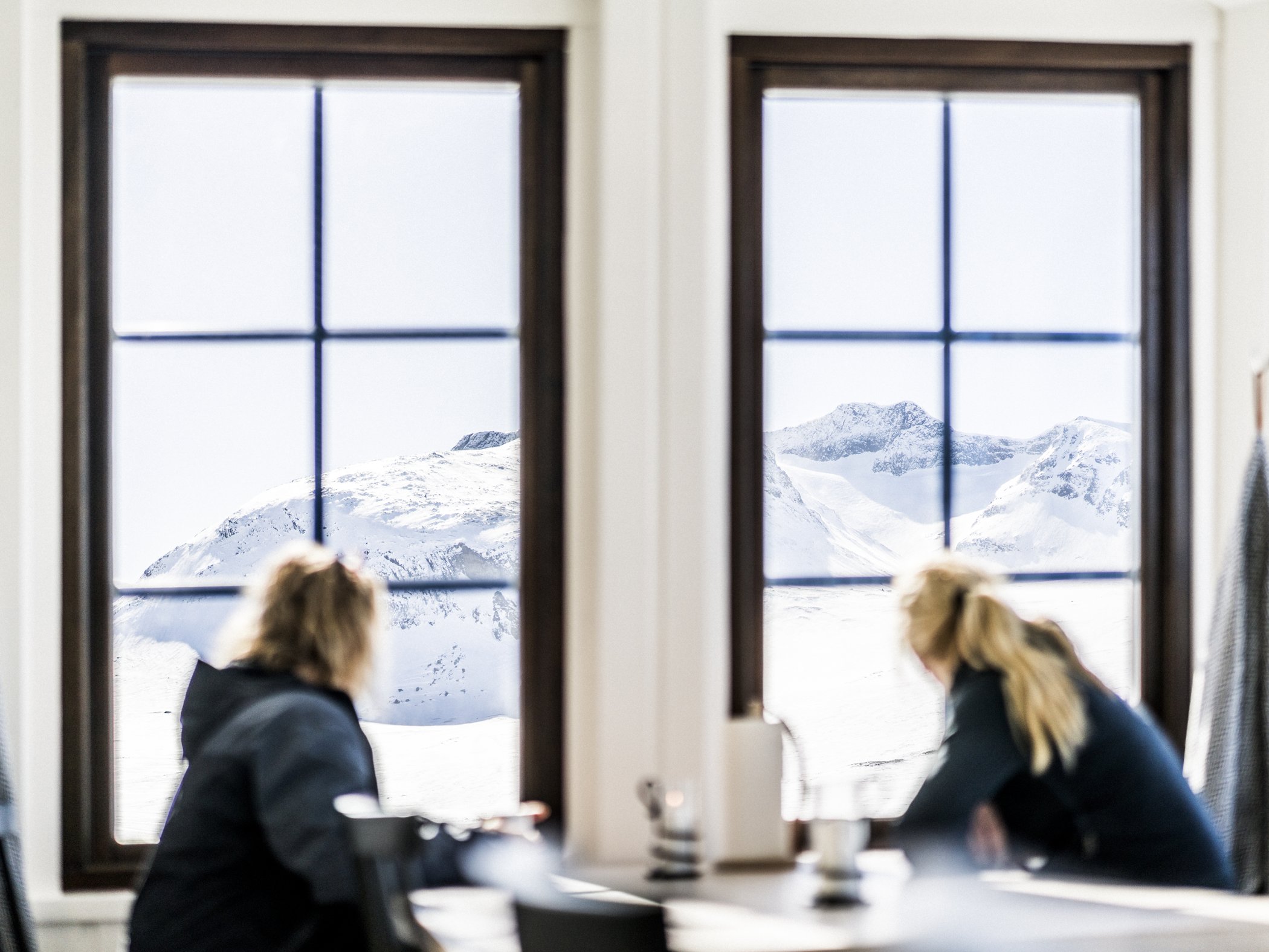 Två personer som tittar ut genom ett fönster på en fjällstation.