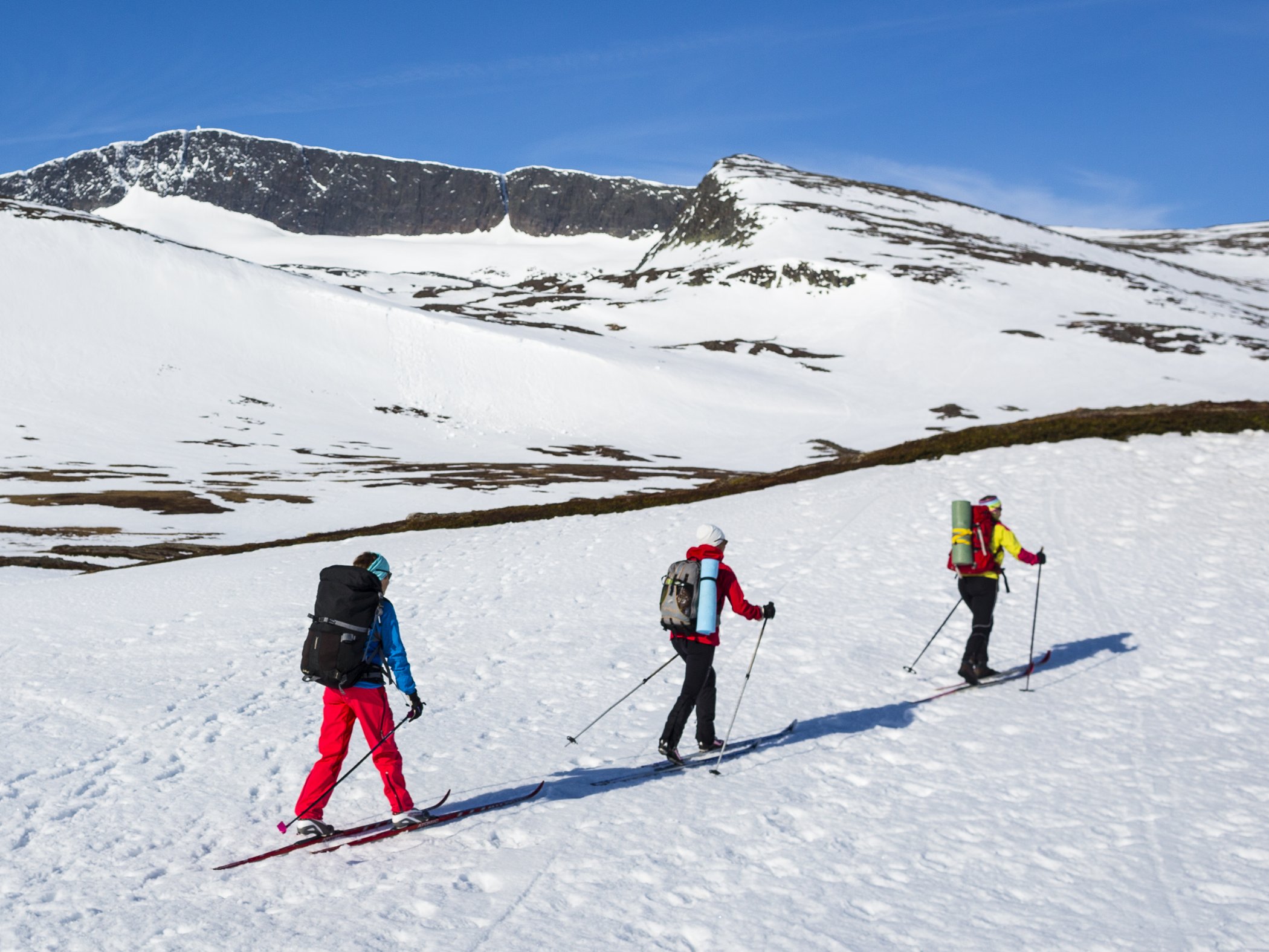 Tre personer ute på turskidor i fjäll.